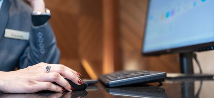 Close-up of a business professional using a computer mouse and keyboard in a modern office environment.